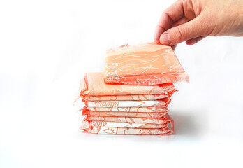 Closeup Stack of women's sanitary napkins individually wrapped in pink on white. Critical days,...