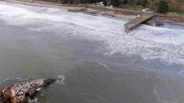 Wreck Of A Concrete Ship Near Seacliff Pier, Both Destroyed By A Powerful Storm In California, USA. aerial pullback