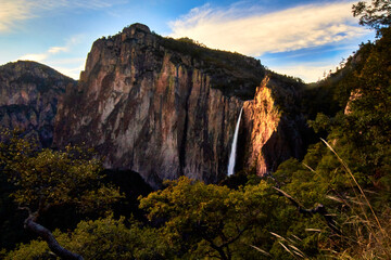 waterfall at sunset in amazing canyon with big mountains and wood around, blue sky with clouds in sierra tarahumara basaseachi chihuahua 