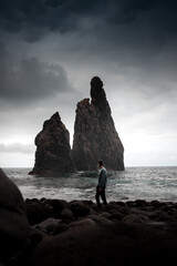 a man standing before Miradouro da Ribera da Janela,The sea stacks located just a few meters from...