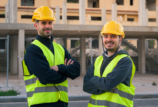 Worker smiling and looking at the camera with construction in the background