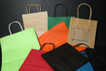 Paper bags of different colors and sizes on a black background. Eco-friendly packaging. Take care of nature. Cardboard. Carrying items. Gift wrap.