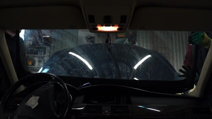 Installing a new windshield on a car. The guys carry glass in their hands .Slow Motion.