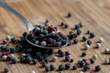 Peppercorns on the spoon. Dried round peppers on a spoon