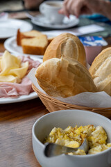 Brazilian breakfast concept in a restaurant setting showing the hand of an unidentified woman, out of focus and unrecognizable, next to a coffee cup