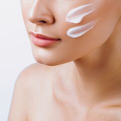 Face of young beautiful woman with cream closeup