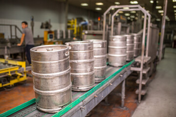 Brewery, bottling beer on aluminum kegs on conveyor lines. Industrial work, automated modern food and beverage production.