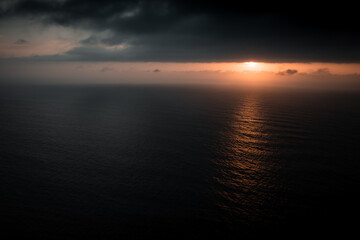 drone view of the ocean and the sun hidden in the clouds