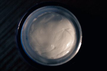 White cream in a small jar. Cosmetic face cream. Top view of a jar of cream for moisturizing and skin care