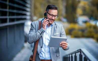 Business people. Businessman holding tablet and checking information while talking with his client via smartphone. Business, lifestyle concept