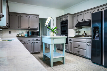 A renovated kitchen in an older home with painted gray cabinets, marble countertops, a small...
