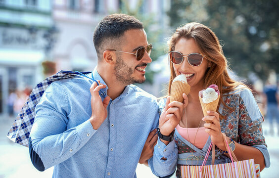 Young couple eating ice cream while enjoying in shopping. Consumerism, lifestyle concept