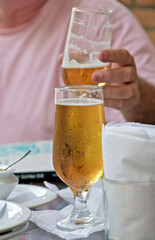Glass of beer on bar table with man in background