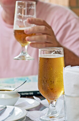 Glass of beer on bar table with man in background