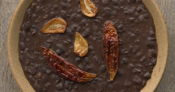 Frijoles refritos with roasted garlic and dried roasted chili on top. Table spin. Seamless loop.