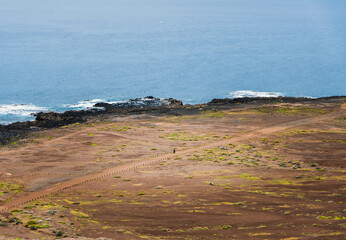 Unrecognizable person walking along the road near the sea