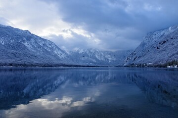 View of Bohinj lake in Gorenjska, Slovenia in winter with forest covered mountains in Julian alps