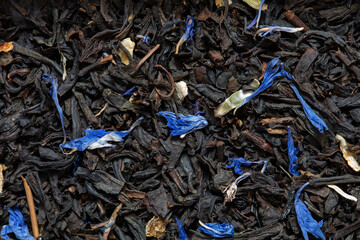 Closeup of black tea with orange, lemon peels and cornflower petals background