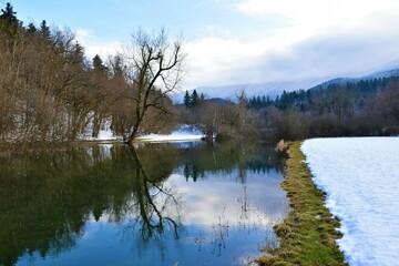 Fototapeta na wymiar View of Rak river in Rakov Skocjan and Javorniki mountains above covered in clouds in Notranjska, Slovenia in winter