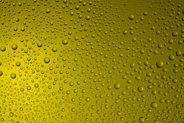 Bubbles and water drops in selective focus on glass, yellow background.