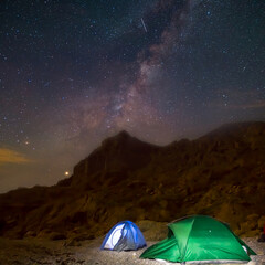night touristic camp in mountain under milky way