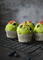 Green tea cupcakes on black oven rack with blue berries