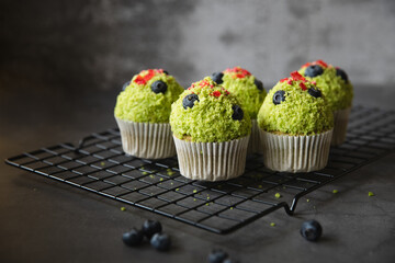 Green tea cupcakes on black oven rack with blue berries