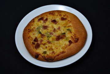 Pizza close-up on a black background. Pizza with meat and tomatoes.