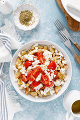 Dakos or koukouvagia salad. Classic recipe Cretan barley rusk salad with fresh tomato, mizithra cheese and oregano. Traditional mediterranean Greek cuisine. Healthy food, diet. Top view
