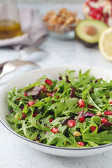 A plate with green rocket salad with pomegranate	