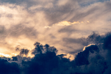 close up of fluffy light and dark cumulus clouds at sunset