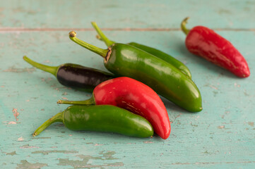 Capsicum annuum Jalapeno chilli hot peppers, group of green and red fruits on wooden colorful vintage table background
