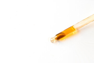 Dropper pipette with yellow liquid gel or serum on white isolated background