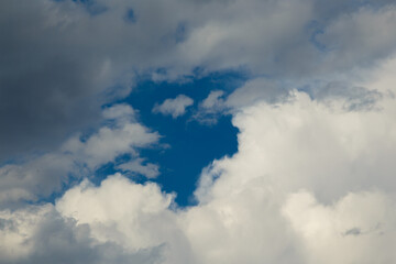 White cloud against stormy sky illuminated by the rays of the setting warm sun against a dark blue clear sky
