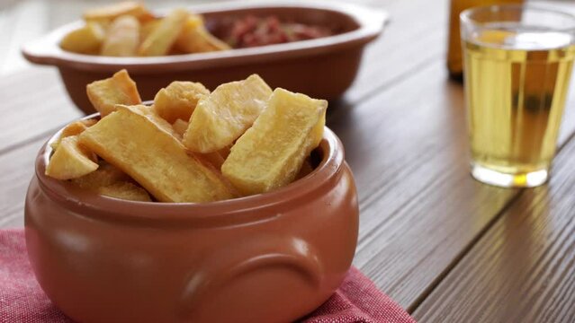 A portion of fried maniocs ( Mandiocas ) on a wooden table, traditional brazilian food.