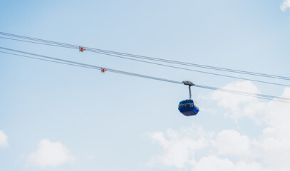 The cabin of the ski lift against the blue sky in the ski resort on a sunny winter day. Lifting the cab up the mountain.