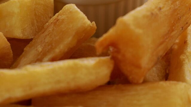 A portion of fried maniocs ( Mandiocas ) on a on a Yellow background, traditional brazilian food