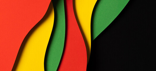 Black History Month color background. Abstract paper cut style composition with layers of geometric shapes and wavy lines in red, yellow, green colors
