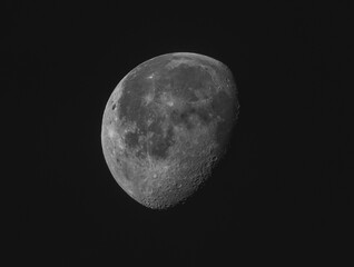 Close up of a waning moon in a clear, dark sky at night exhibiting details of surface structure and...