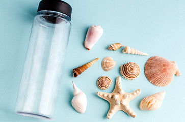 Seashells and a water bottle on a blue background with space for text