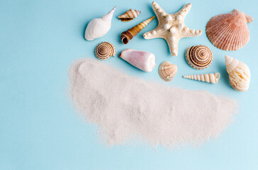 Seashells and clean sand on a blue background with space for text