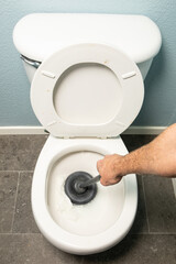 unclogging clogged toilet with plunger 