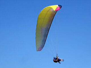 Tandem Paraglider flying in a blue sky	