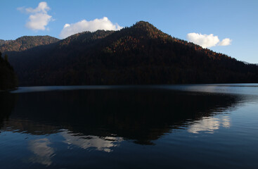 A lake in the mountains with a mirror image of the silhouette of a high hill on the water surface