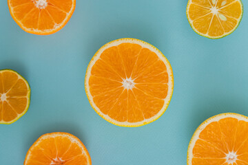 Top view of oranges and mandarin limes slices creating pattern over light blue background