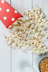 popcorn bag, popcorn kernels and salt on a white wooden table, top view