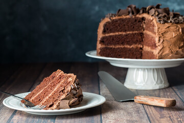 A homemade three layer low sugar chocolate cake with one slice in front.