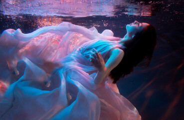 Woman model, ballerina underwater in a fluttering dress. Soft blurred focus.