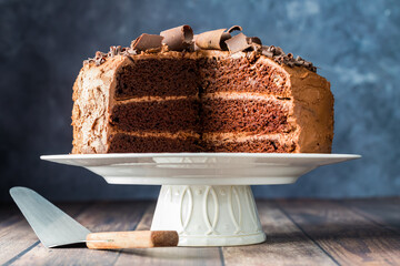 A triple layer chocolate cake cut into, decorated with chocolate curls.