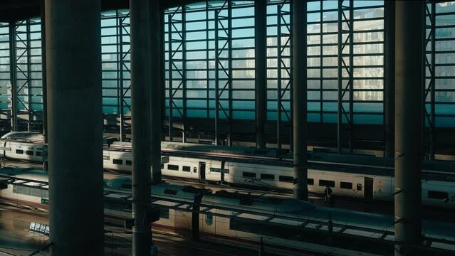 Cinematic view of famous Atocha high speed railway station. Bullet train arrives at the track. Passenger travelers hurries to his car or wagon. Madrid, January 2023. 